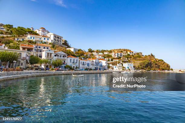 Sunny autumn day in Evdilos Village in Ikaria. Panoramic view of the traditional picturesque fishing village with the wooden boats in the harbor, one...