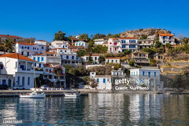 Sunny autumn day in Evdilos Village in Ikaria. Panoramic view of the traditional picturesque fishing village with the wooden boats in the harbor, one...