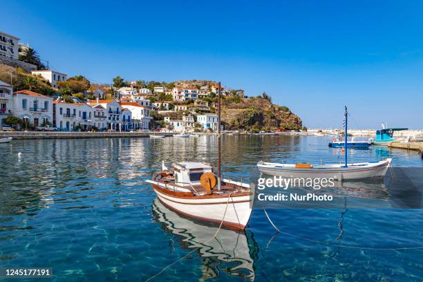 Sunny autumn day in Evdilos Village in Ikaria. Panoramic view of the traditional picturesque fishing village with the wooden boats in the harbor, one...