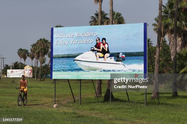 Cuban man rides his bicycle past a large billboard promoting tourism in Varadero, Cuba.