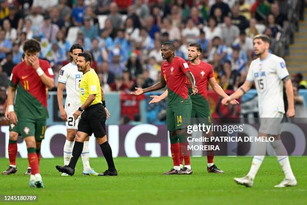 Portugal's midfielder William Carvalho and Portugal's defender Ruben Dias argue with Iranian referee Alireza Faghani during the Qatar 2022 World Cup...