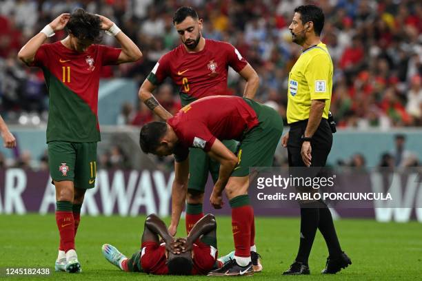 Portugal's defender Ruben Dias checks on Portugal's defender Nuno Mendes lying on the pitch after he sustained an injury during the Qatar 2022 World...