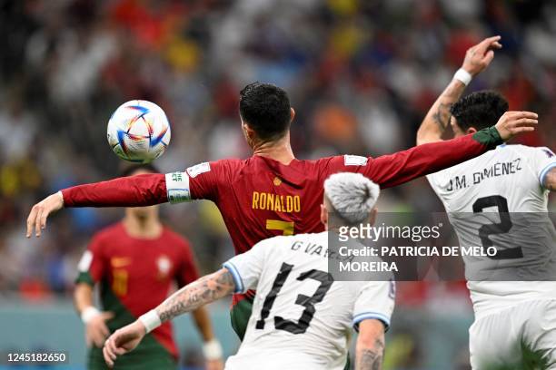 Portugal's forward Cristiano Ronaldo fights for the ball with Uruguay's defender Guillermo Varela and Uruguay's defender Jose Maria Gimenez during...