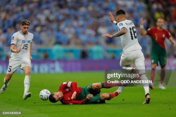 Portugal's forward Cristiano Ronaldo falls on the pitch after fighting for the ball with Uruguay's defender Mathias Olivera during the Qatar 2022...
