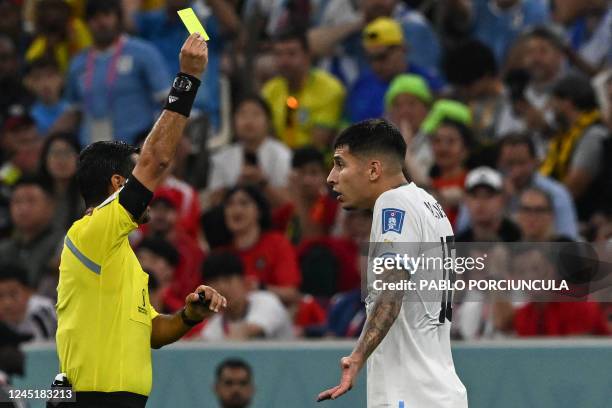 Uruguay's defender Mathias Olivera reacts as he receives a yellow card from Iranian referee Alireza Faghani during the Qatar 2022 World Cup Group H...