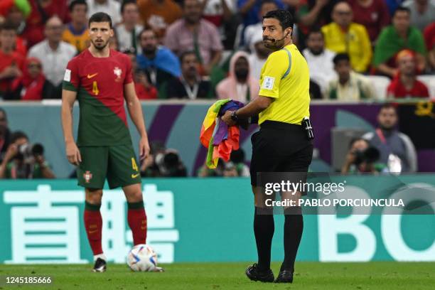 Iranian referee Alireza Faghani holds a rainbow-coloured Peace flag after Mario Ferri who calls himself "The Falcon" invaded the pitch waving it...