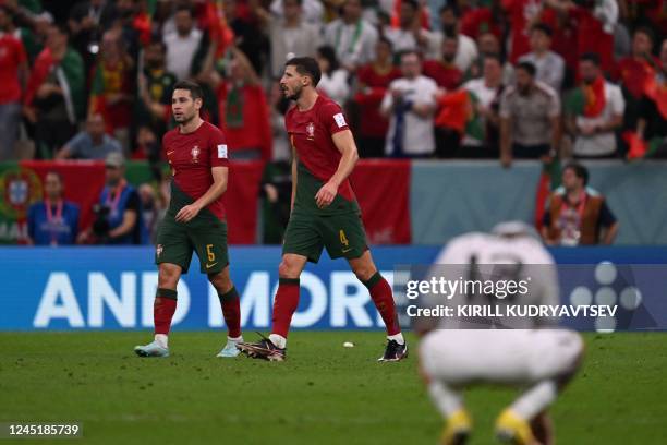 Portugal's defender Raphael Guerreiro , Portugal's defender Ruben Dias and Uruguay's defender Guillermo Varela gesture at the end of the Qatar 2022...