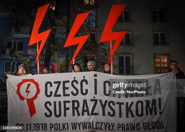 Activists hold a banner with words 'Honor And Glory To The Suffragettes' and three red lightning bolts, the main symbol of the pro-choice movement,...