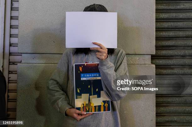 Protester holds up a sign and a blank piece of paper during a demonstration. Dozens of protesters gather in solidarity with those in China rallying...