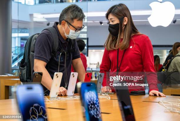 An employee assists a customer with purchasing an Apple iPhone 14 at its official store in Hong Kong.