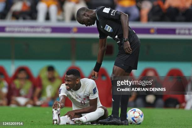 Gambian referee Bakary Gassama greets Qatar's forward Mohammed Muntari at the end of the Qatar 2022 World Cup Group A football match between the...