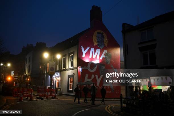 People walk past a mural featuring footballers Gareth Bale, Neco Williams and Harry Wilson by artists Liam Stokes-Massey aka Pencilcraftsman and Adam...