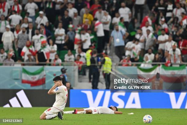 Iran's midfielder Ali Karimi and Iran's defender Ramin Rezaeian react after the Qatar 2022 World Cup Group B football match between Iran and USA at...