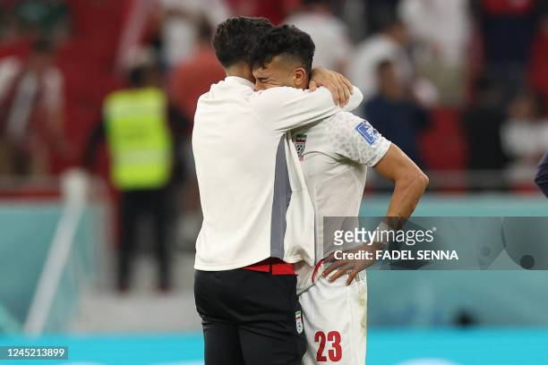 Iran's defender Ramin Rezaeian is comforted as he cries at the end of the Qatar 2022 World Cup Group B football match between Iran and USA at the...