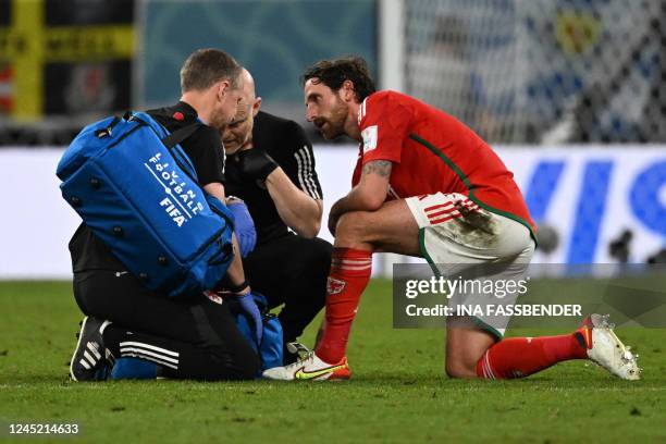 Wales' midfielder Joe Allen receives medical attention after being injured during the Qatar 2022 World Cup Group B football match between Wales and...