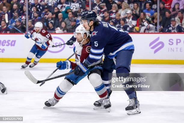 Brenden Dillon of the Winnipeg Jets battles with Andrew Cogliano of the Colorado Avalanche as they keep an eye on the play during third period action...
