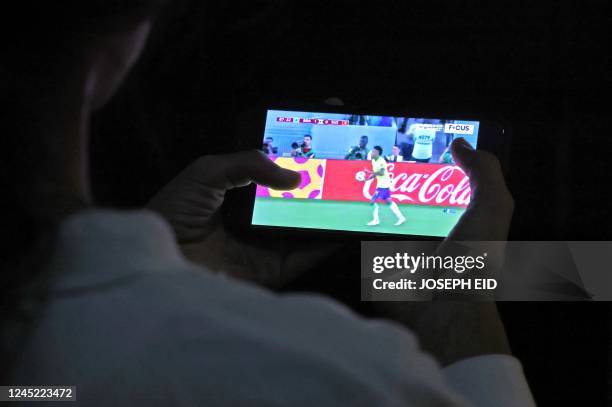 Girl watches on her mobile phone a streaming broadcast of the FIFA World Cup 2022 group G soccer match between Brazil and Switzerland, in Beirut on...