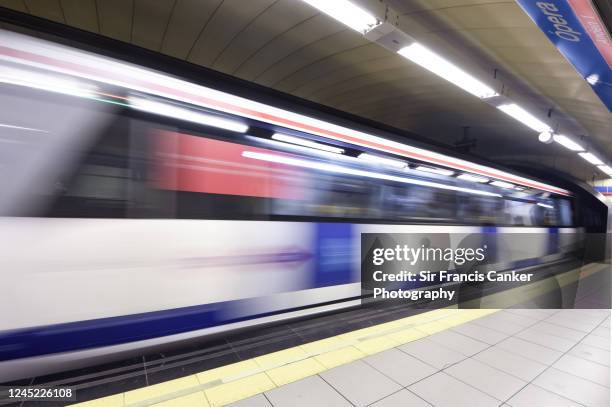 blurred blue metro train passing fast thru a subway station in madrid, spain - 經過 個照片及圖片檔
