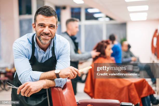hairdresser stands in a hairdressing studio - male barber stock pictures, royalty-free photos & images