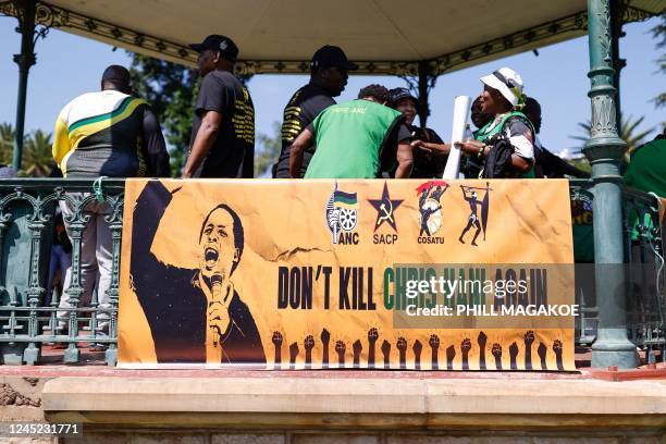 Members of the ruling African National Congress and the South African Communist Party stand next to a poster reading Dont Kill Chris Hani Again...