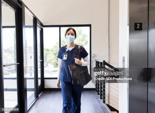 young adult nurse arrives for work at medical clinic - social distancing elevator stock pictures, royalty-free photos & images