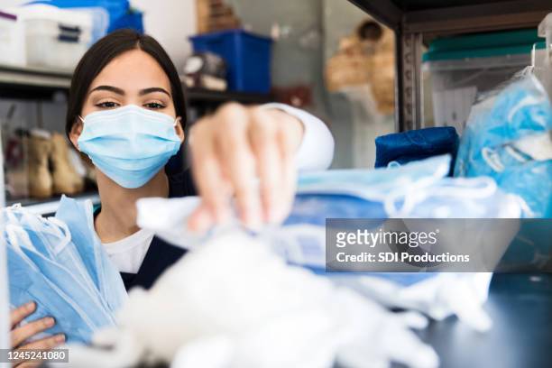 nurse reaches for supplies in clinic supply room - storage room stock pictures, royalty-free photos & images