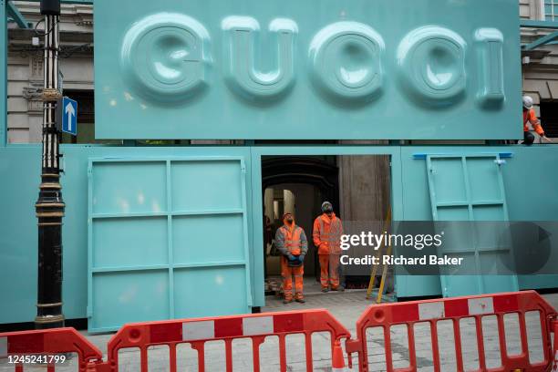 Workmen prepare to position a Gucci logo sign above the frontage of its new flagship store on Bond Street during a period of construction and...