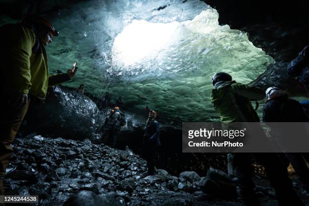 People wearing safety clothing and equipment are seen walking through the corridors of the Blue Cave on the Vatnajökull glacier. Skaftafell, October...