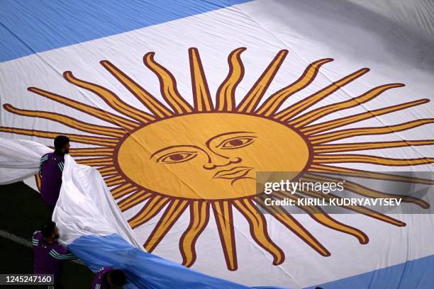 Volunteers carry an Argentina flag before the start of the Qatar 2022 World Cup Group C football match between Poland and Argentina at Stadium 974 in...