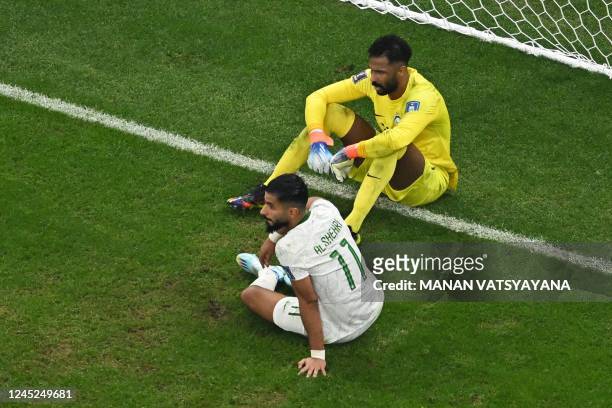 Saudi Arabia's goalkeeper Mohammed Al-Owais and Saudi Arabia's forward Saleh Al-Shehri sit on the ground after Mexico's forward Henry Martin scored...