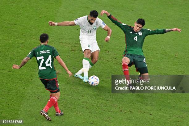 Saudi Arabia's forward Saleh Al-Shehri is challenged by Mexico's midfielder Edson Alvarez and Mexico's midfielder Luis Chavez during the Qatar 2022...
