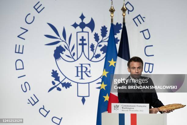 French President Emmanuel Macron holds a baguette as he speaks during a reception honoring the French community in the US, at the French Embassy in...