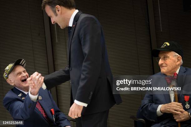 Veteran George Idelson watches as WWII veteran Carl Felton shakes hands with French President Emmanuel Macron after he awarded them the Legion...
