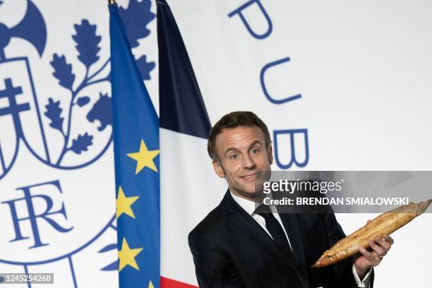 French President Emmanuel Macron holds a baguette during a reception honoring the French community in the US, at the French Embassy in Washington,...