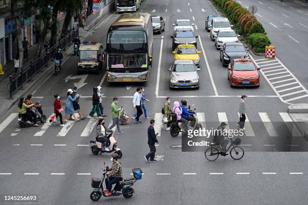 This photo taken on November 30, 2022 shows people walking across a street in Haizhu district, Guangzhou city, in China's southern Guangdong...