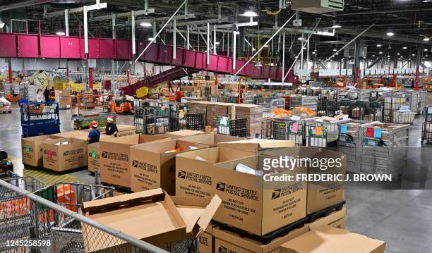 Postal Service employees, some wearing Santa hats, sort mail at the Los Angeles Processing and Distribution Center in preparation for another busy...