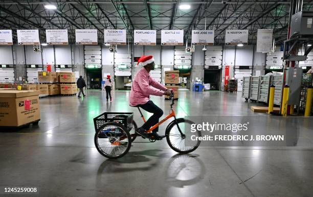 Postal Service employee wearinga Santa hat, bikes through the Los Angeles Processing and Distribution Center where mail is sorted in preparation for...