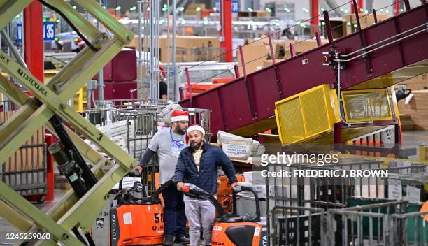 Postal Service employees, some wearing Santa hats, sort mail at the Los Angeles Processing and Distribution Center in preparation for another busy...