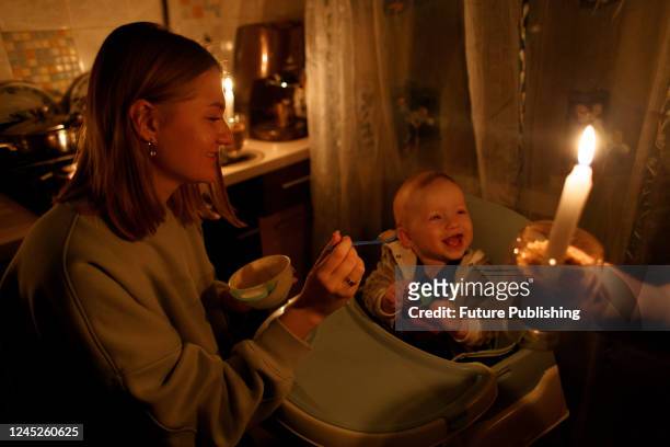 Yaryna feeds her son Vladyslav, who was born two days prior to Russia's full-scale invasion of Ukraine, by candlelight during a power cut caused by...