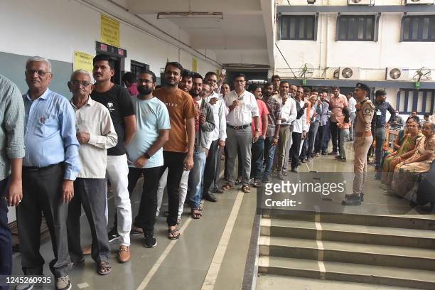 People wait in line to cast their vote at a polling station during Phase 1 of Gujarat's assembly elections in Surat on December 1, 2022.