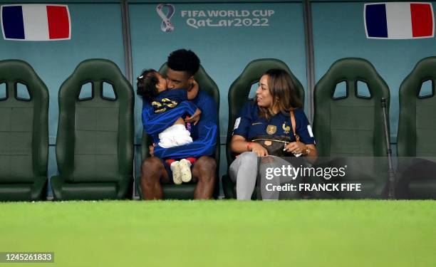 France's forward Kingsley Coman kisses his child as he sits next to his partner Sabrina Duvad after the Qatar 2022 World Cup Group D football m atch...