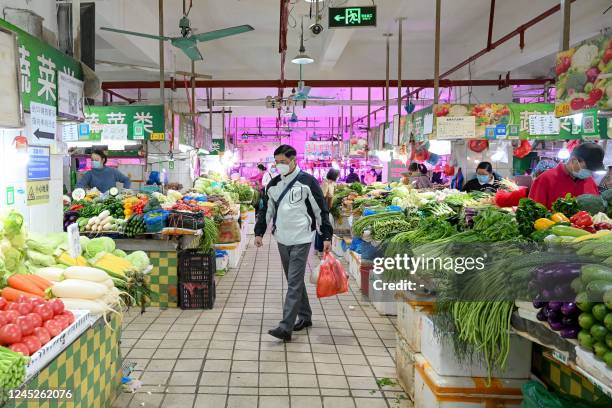 Man shops for food at a market in Haizhu district, Guangzhou city, in China's southern Guangdong province on December 1 following the easing of...