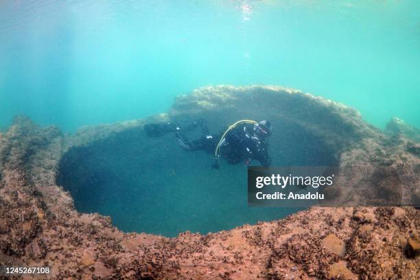 Diver swims through the historical ruins of Ottoman, Byzantine, Roman, Assyrian, and Seljuk origin submerged in water at Dicle Dam Lake in...