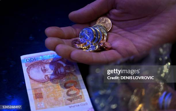 Man holds 100 kuna and a package containing euros, in Zagreb on December 1, 2022. With inflation mounting and precarious geopolitical headwinds...