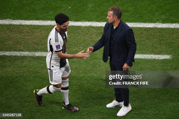 Germany's midfielder Ilkay Gundogan shakes hands with Germany's coach Hans-Dieter Flick after being substituted during the Qatar 2022 World Cup Group...