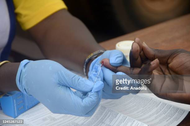 Group of volunteer health workers take blood samples from participant for AIDS tests within the events of December 1 World AIDS Day in Kampala,...