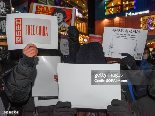 Protesters hold placards and blank white paper during a vigil in Seoul commemorating victims of China's Covid Zero policy. Blank white paper...