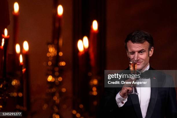 French President Emmanuel Macron winks as he shares a toast with U.S. President Joe Biden at the state dinner on the South Lawn of the White House on...
