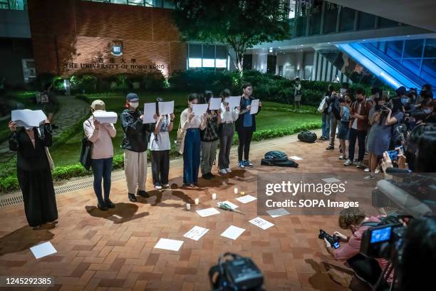 Protesters seen holding blank white papers while standing next to burning candles during the demonstration. Blank white paper symbolizes the defiance...