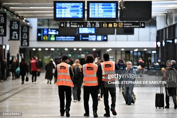 Employees wearing a orange jacket with the logo SNCF walk at Gare de Montparnasse in Paris, on December 2, 2022 during a strike organised by SNCF...